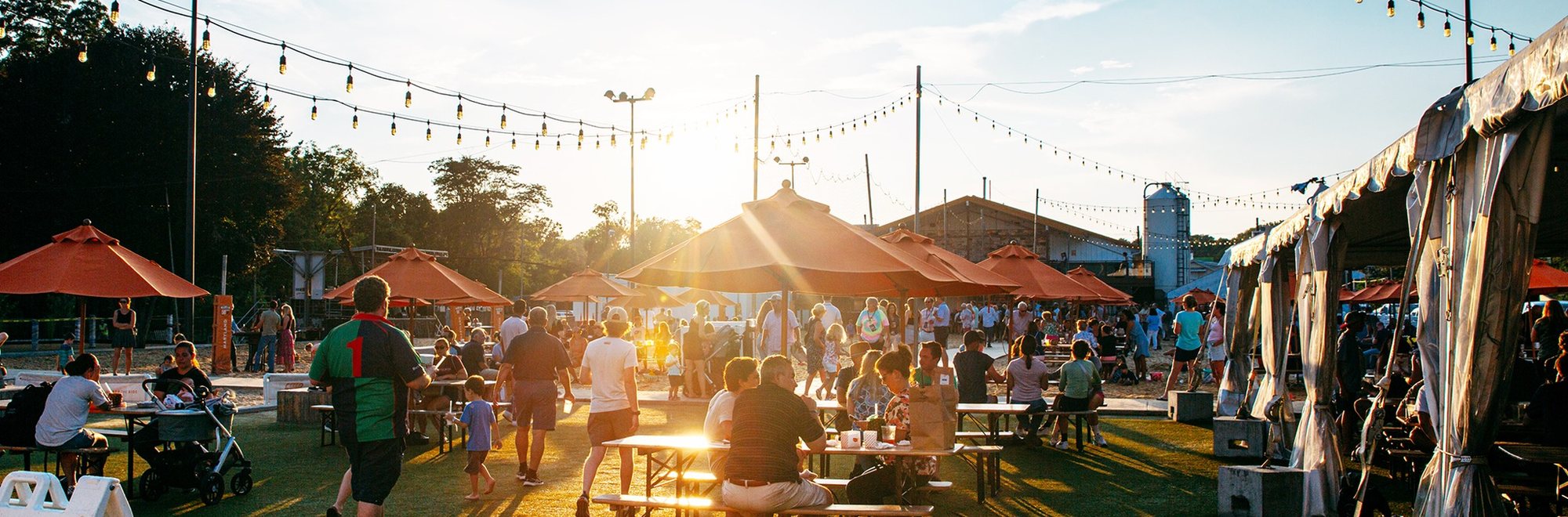 Sunset over the Fifty West beer garden with families at picnic tables